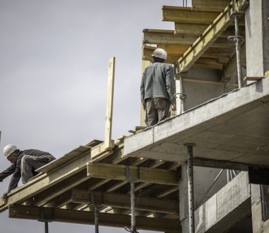 Dos obreros trabajando en la costrucción del esqueleto de hormigón de un edificio.