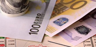 Billetes de cien y doscientos euros sobre una gráfica con una flecha que señala un descenso del valor.