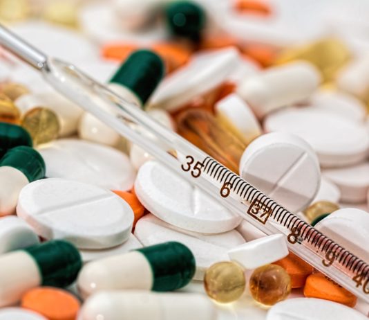 Termómetro de mercurio sobre pastillas de diversas formas y colores.
