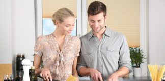 Mujer y hombre jóvenes cocinan en su casa