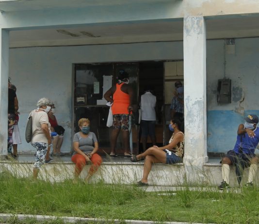 Clientes mantienen la distancia y usan mascarillas protectoras para prevenir el contagio de la enfermedad covid-19 mientras aguardan en el exterior de una farmacia para adquirir medicamentos, en el municipio de 10 de Octubre de La Habana, en Cuba. Foto: Jorge Luis Baños/IPS