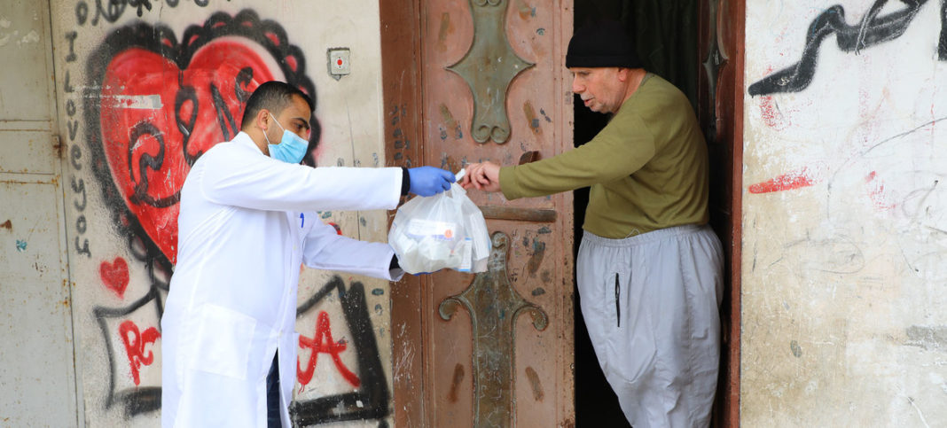 © UNRWA/Khalil Adwan Un trabajador de UNRWA le ayuda con medicamentos a un anciano palestino en la Franja de Gaza