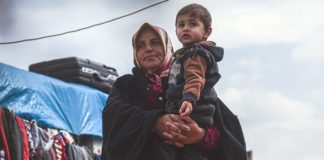 OCHA/Steve Hafez Una mujer viuda carga a su nieto en un campamento de desplazados en la provincia siria de Idlib