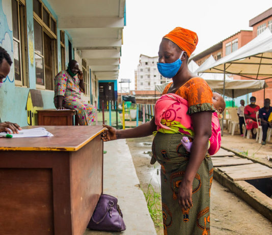 PMA/Damilola Onafuwa Mujeres nigerianas toman vales de alimentos como parte de un programa de apoyo a las familias que luchan contra el confinamiento de la COVID-19