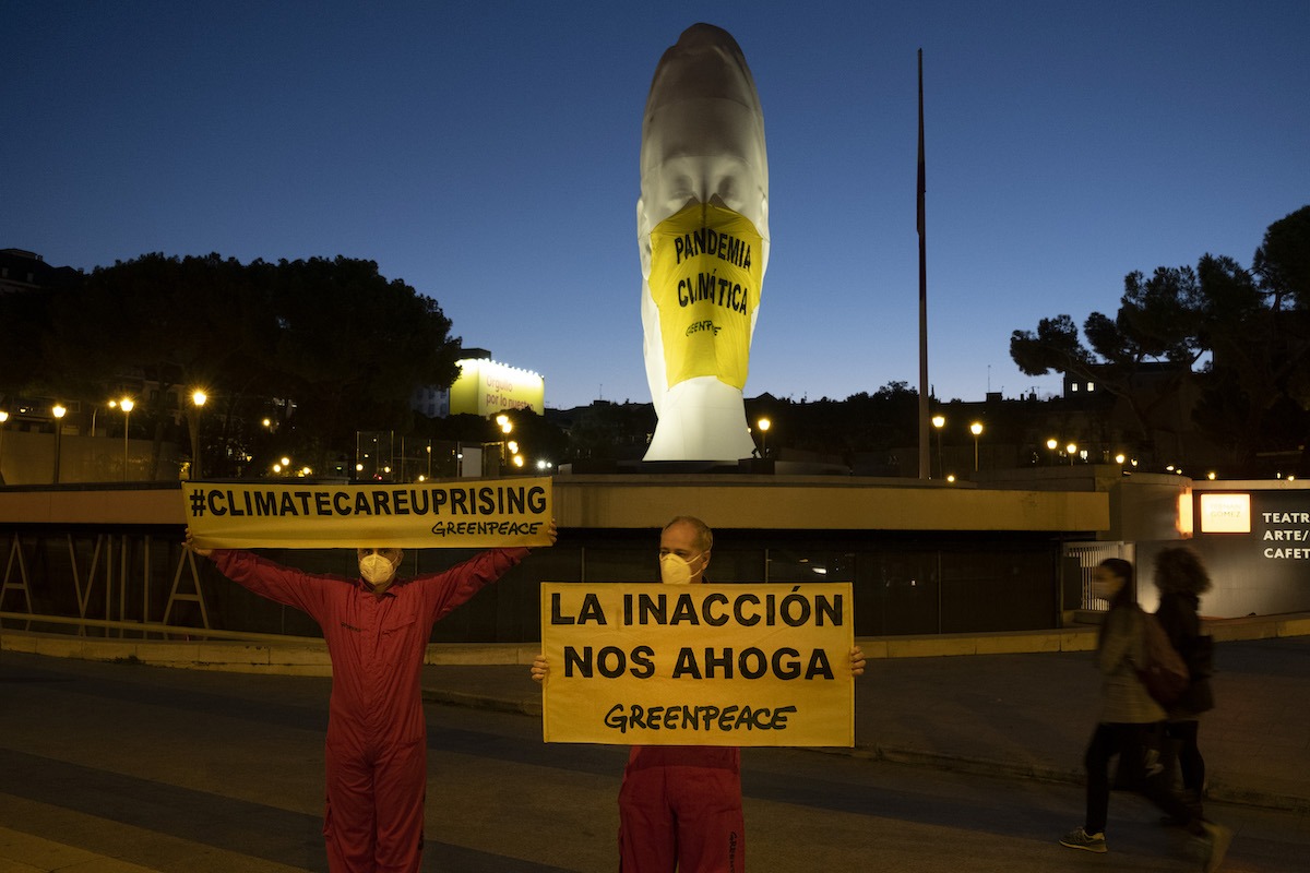 Activistas de Greenpeace han colocado a primera hora de esta mañana una mascarilla gigante (4x5 metros) en una escultura de la plaza de Colón (Madrid) en la que se lee 