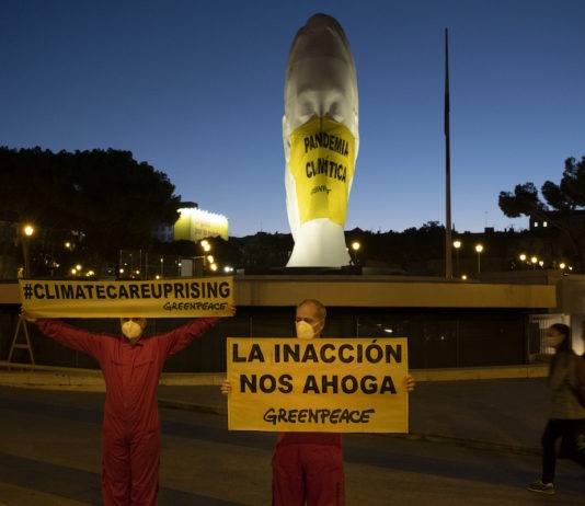 Activistas de Greenpeace han colocado a primera hora de esta mañana una mascarilla gigante (4x5 metros) en una escultura de la plaza de Colón (Madrid) en la que se lee "Pandemia Climática". A su lado, otra pancarta señala "La inacción nos ahoga".