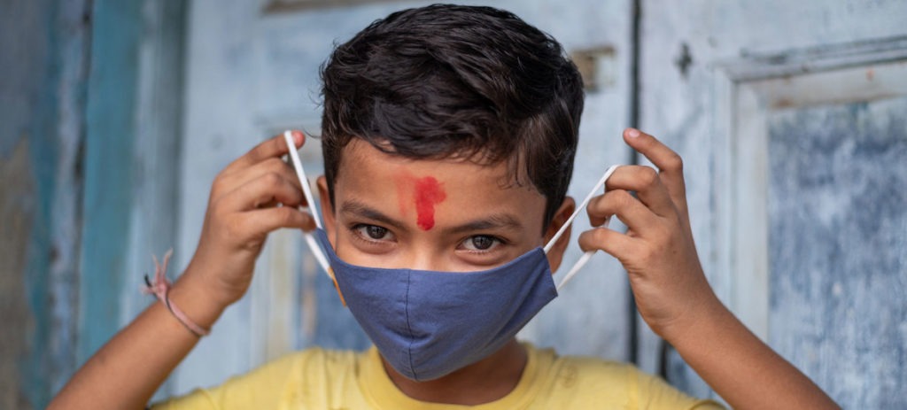 UNICEF/Vinay Panjwani: Un niño de 11 años en India muestra cómo ponerse correctamente una máscara para protegerse del COVID-19.