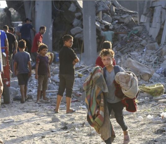 Gaza: un niñoo saca sus pertenencias de un edificio bombardeado ©UNRWA