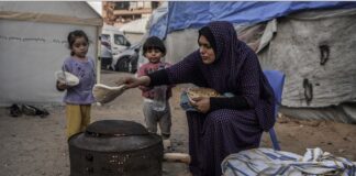 ©UNICEF/Abed Zagout: Una madre prepara comida para sus hijos en el exterior de su casa improvisada en un campo de refugiados de jan Yunis, Gaza