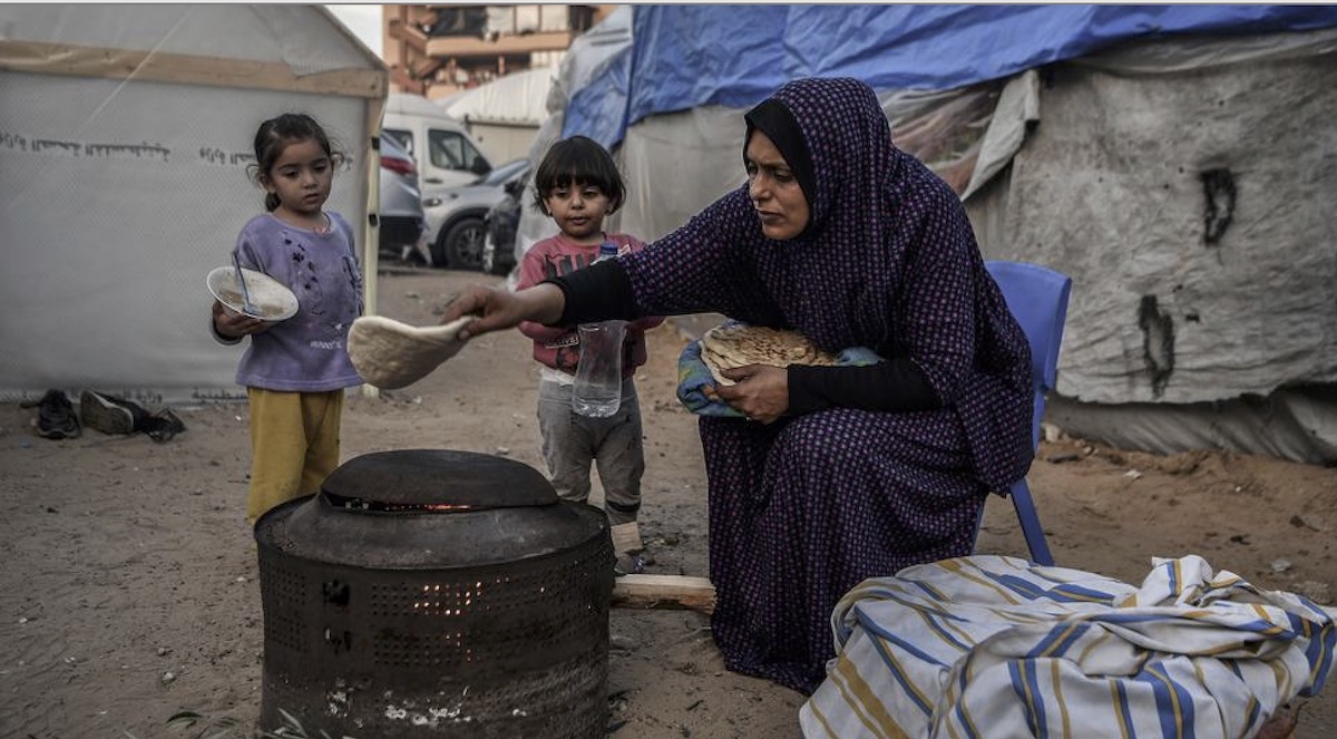 ©UNICEF/Abed Zagout: Una madre prepara comida para sus hijos en el exterior de su casa improvisada en un campo de refugiados de jan Yunis, Gaza