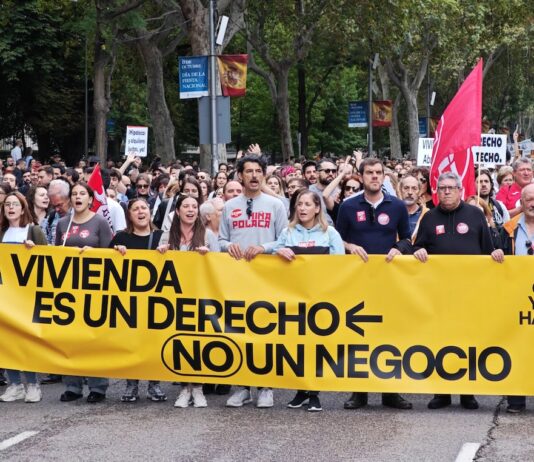 Manifestantes por la vivienda pública y el alquiler asequible en Madrid tras la pancarta de cabeza