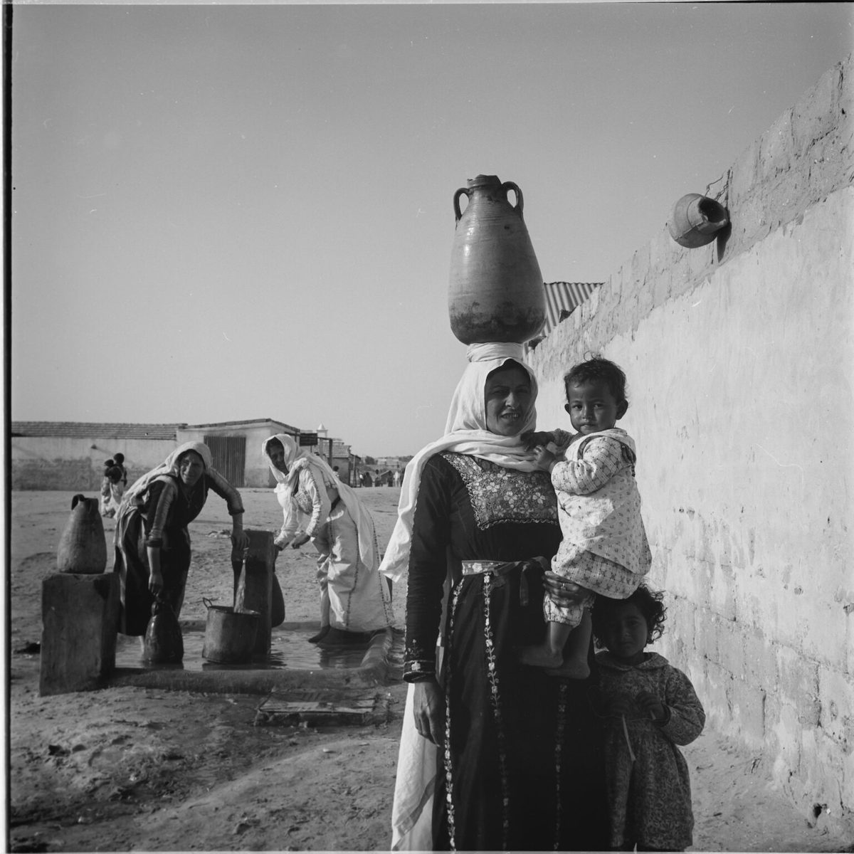 Mujeres refugiadas de Palestina recogen agua en un punto público en el campamento de Jabalia, en la franja de Gaza. © 1965 Archivo de UNRWA, fotógrafo desconocido