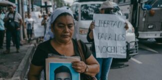 Una mujer muestra una fotografía de su hijo, detenido en una protesta en San Salvador durante el estado de excepción en mayo de 2024 ©Carlos Barrera / HRW