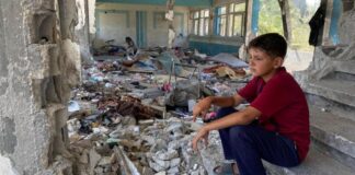 Niño sentado en unos escalones de lo que fue su escuela en Nuseirat, en la Franja de Gaza. @Unrwa