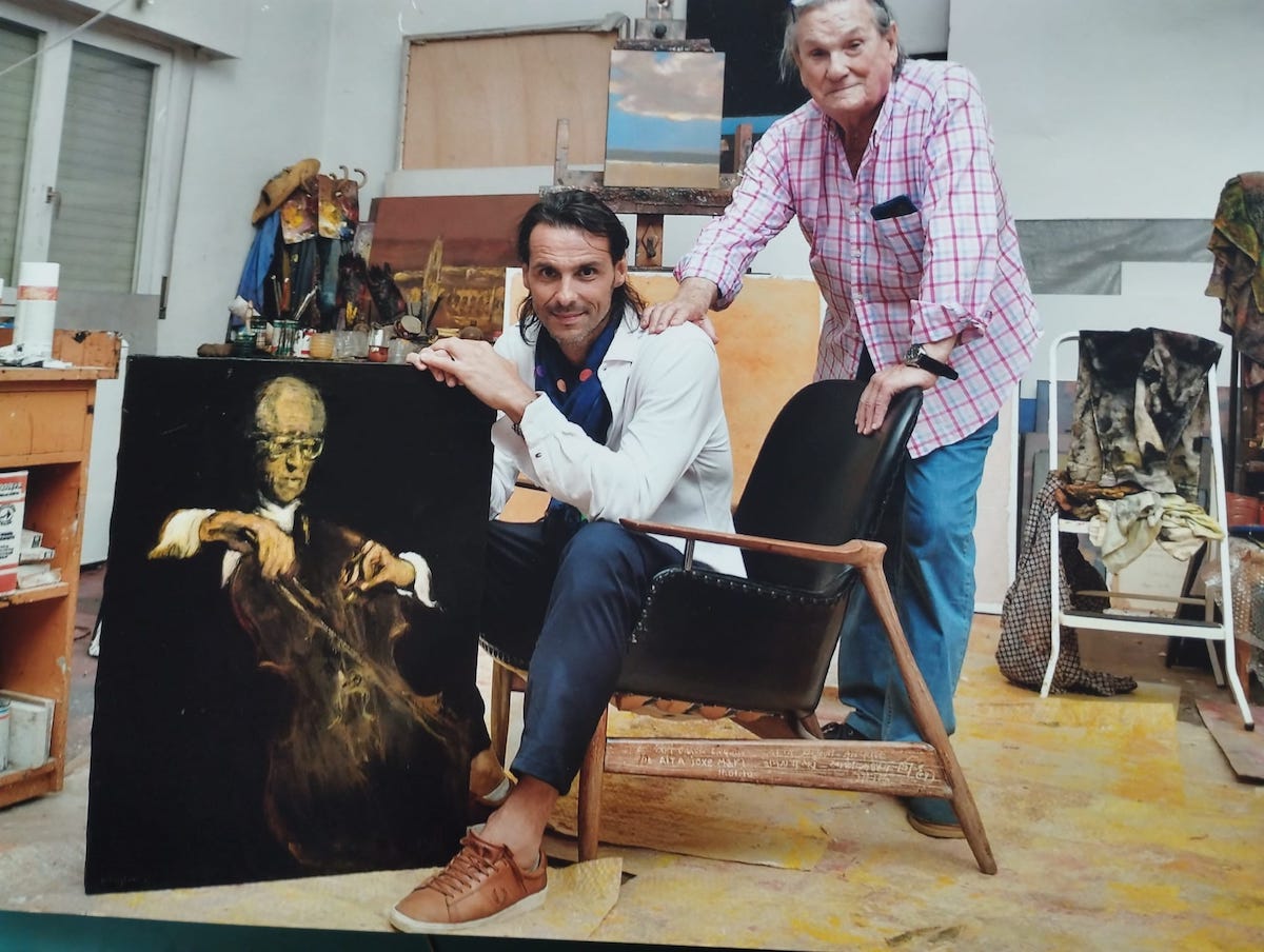García Ergüin en su estudio, con el bailarin de ballet Igor Yebra que sujeta el cuadro de Rostropovich.