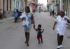 Una madre afrodescendiente camina con su hijo de la mano y su pequeña bebe en brazos, cerca de una enfermera, por una calle céntrica de La Habana. ©Jorge Luis Baños / IPS