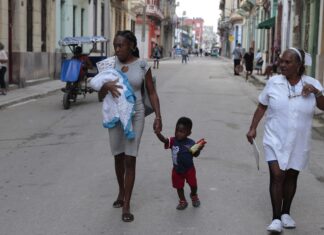 La crisis en Cuba agrava las desigualdades de la población negra Una madre afrodescendiente camina con su hijo de la mano y su pequeña bebe en brazos, cerca de una enfermera, por una calle céntrica de La Habana. ©Jorge Luis Baños / IPS
