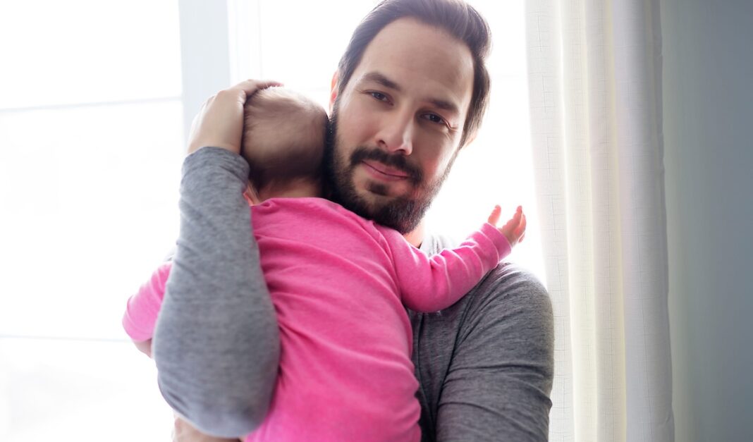 Father consoling his baby girl close to the window